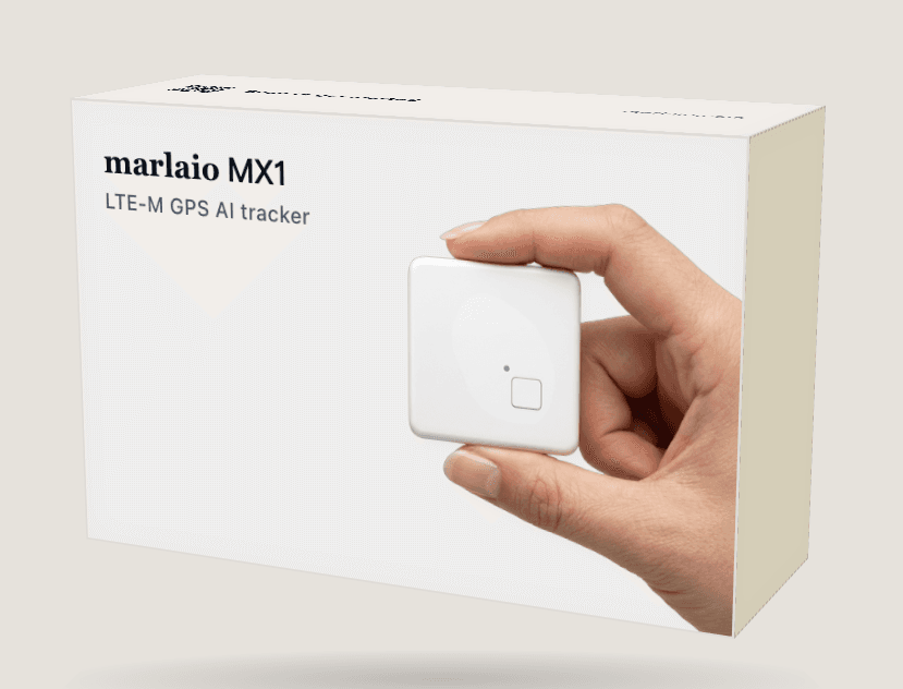 Render of the marlaio MX1 box: a pale sleeve printed with “marlaio MX1 — LTE-M GPS AI tracker” and a hand holding the white unit.